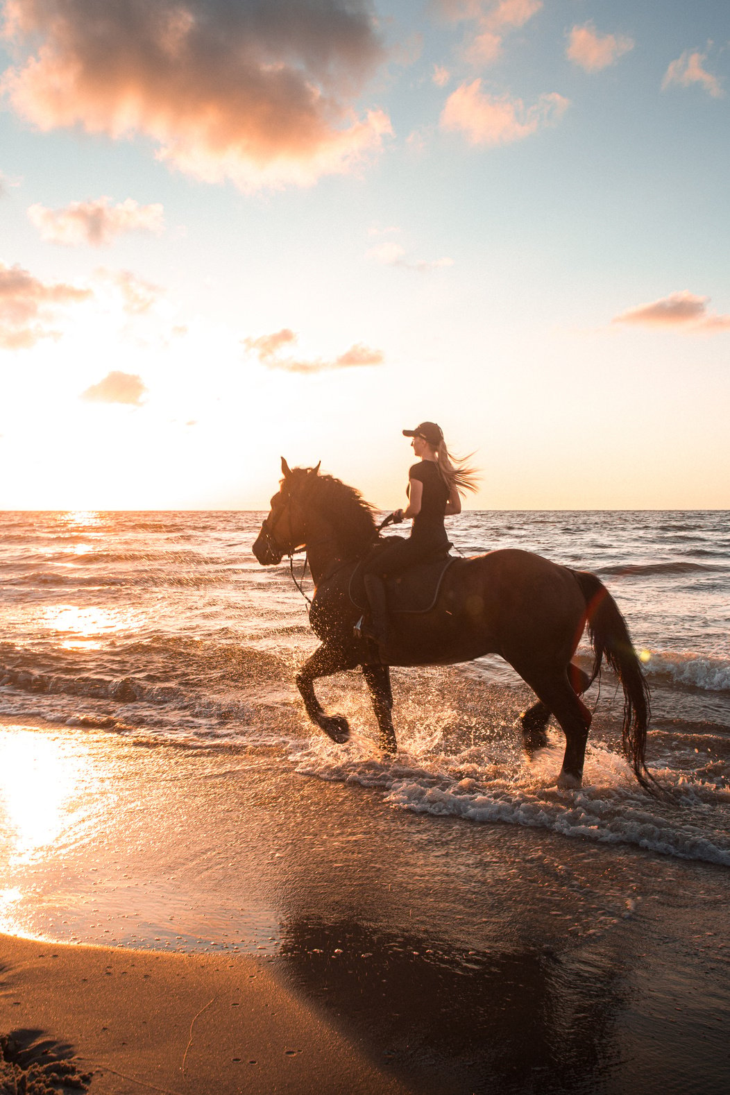 A Woman Riding a Horse on the Beach during Sunset